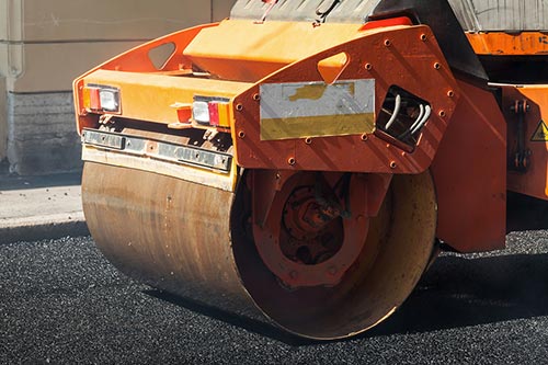 entrée de garage en asphalte avec machinerie entrain d'écraser l'asphalte